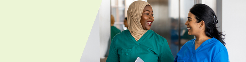 Two smiling healthcare professionals walking down a hall together