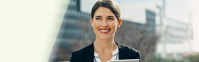 Smiling professional standing outside in front of office buildings holding tablet
